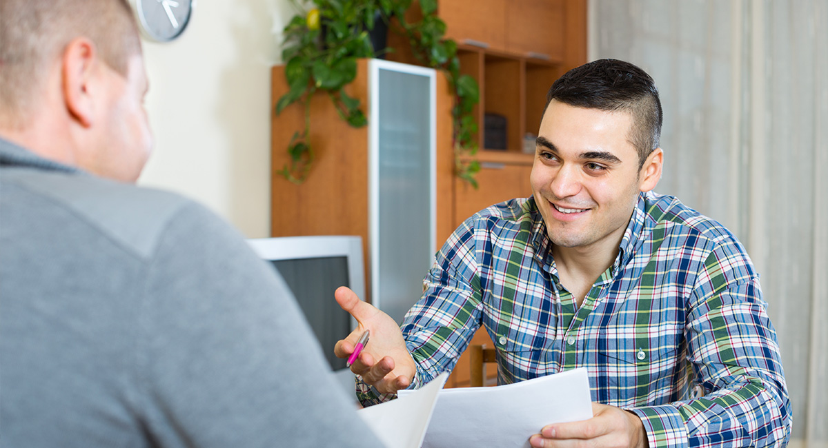 Ein Betreuer im Gespräch mit einem Menschen mit Autismus