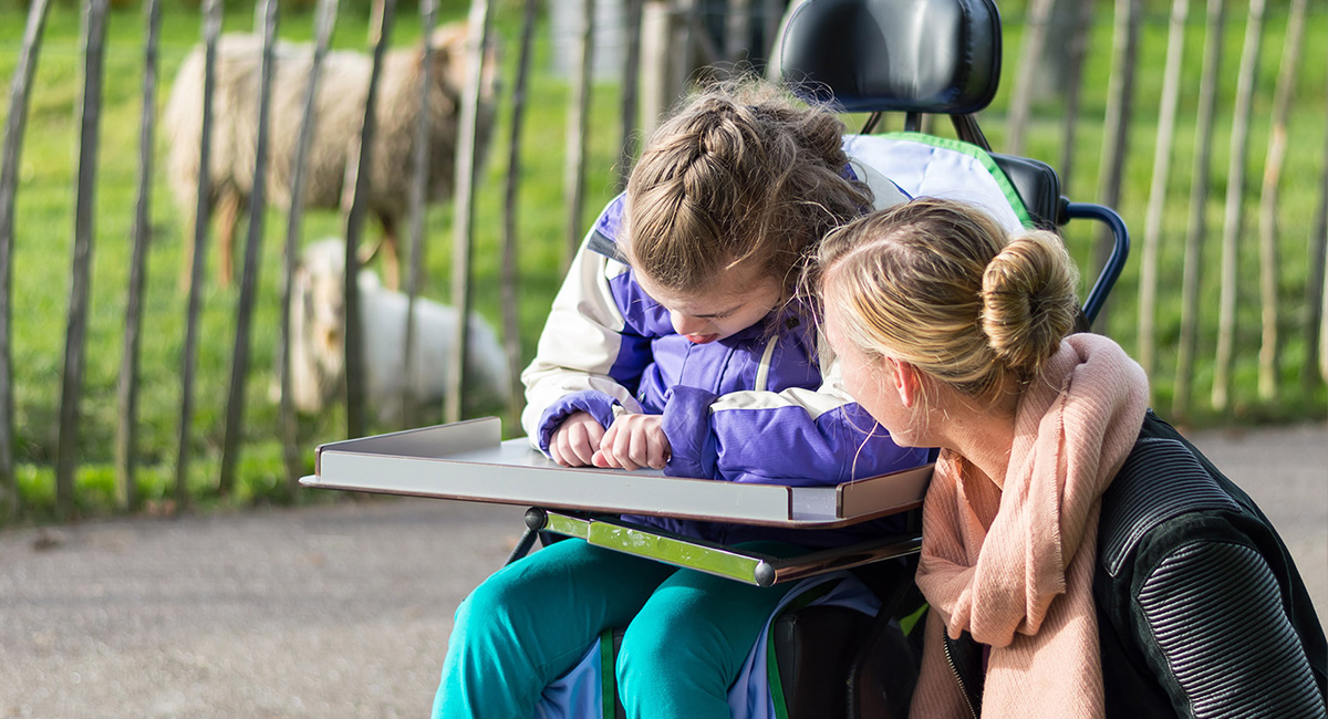 Ein Mädchen besucht mit einer Begleiterin einen Streichelzoo
