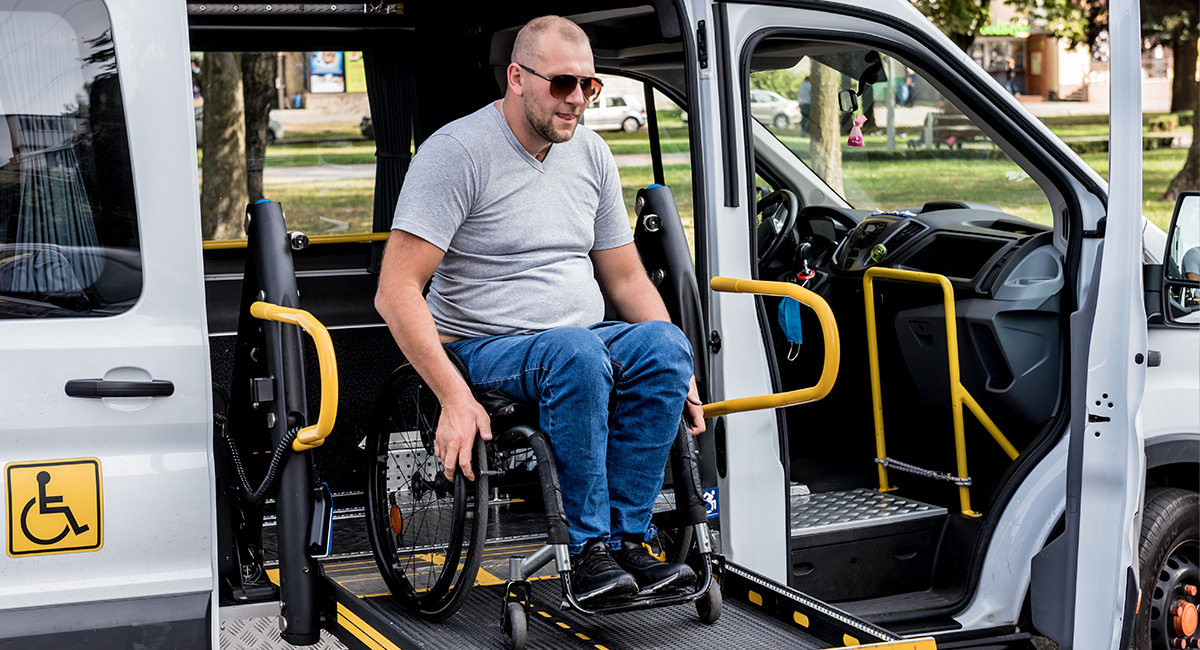 Ein Mann im Rollstuhl nutzt die Hebebhüne des Fahrdienstes