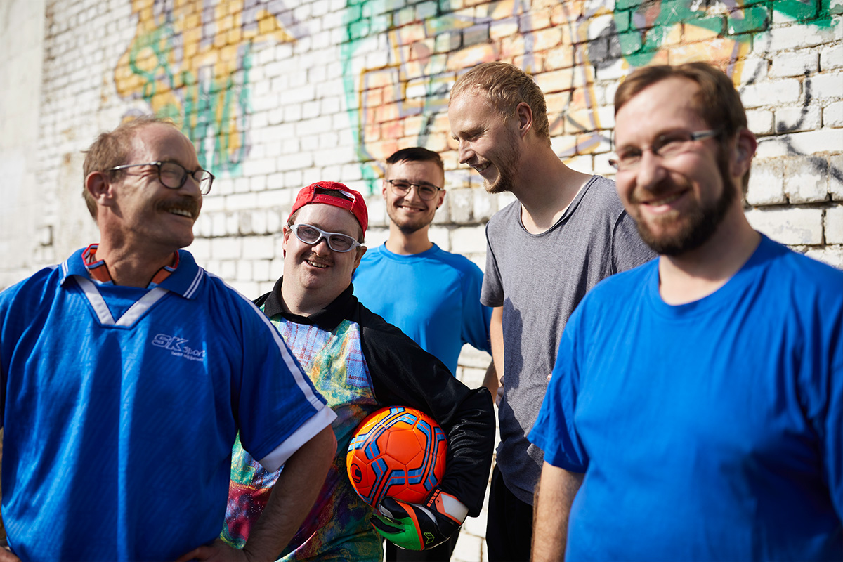 Eine Gruppe aus Männern mit und ohne Behinderung freut sich über das gemeinsame Fußballspielen