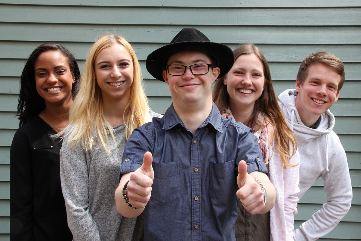 Junge Menschen lächeln in eine Kamera