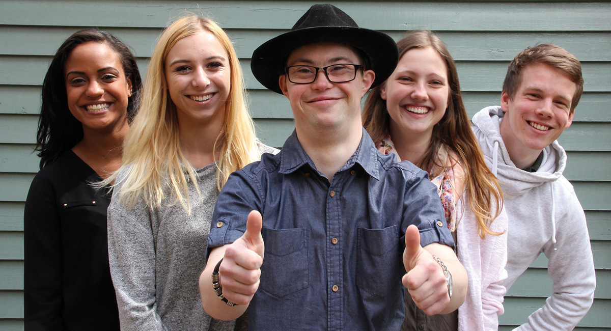 Junge Menschen lächeln in eine Kamera