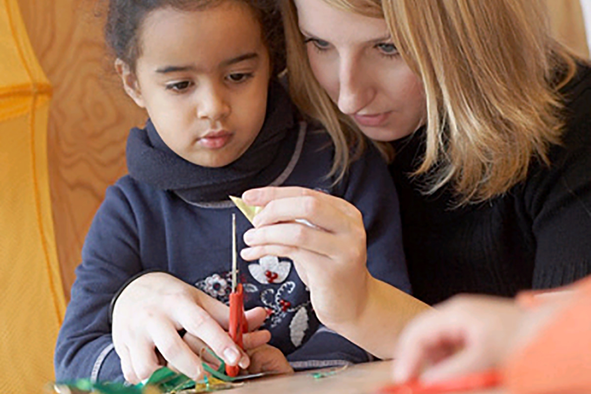 Eine junge Frau bastelt mit einem Mädchen