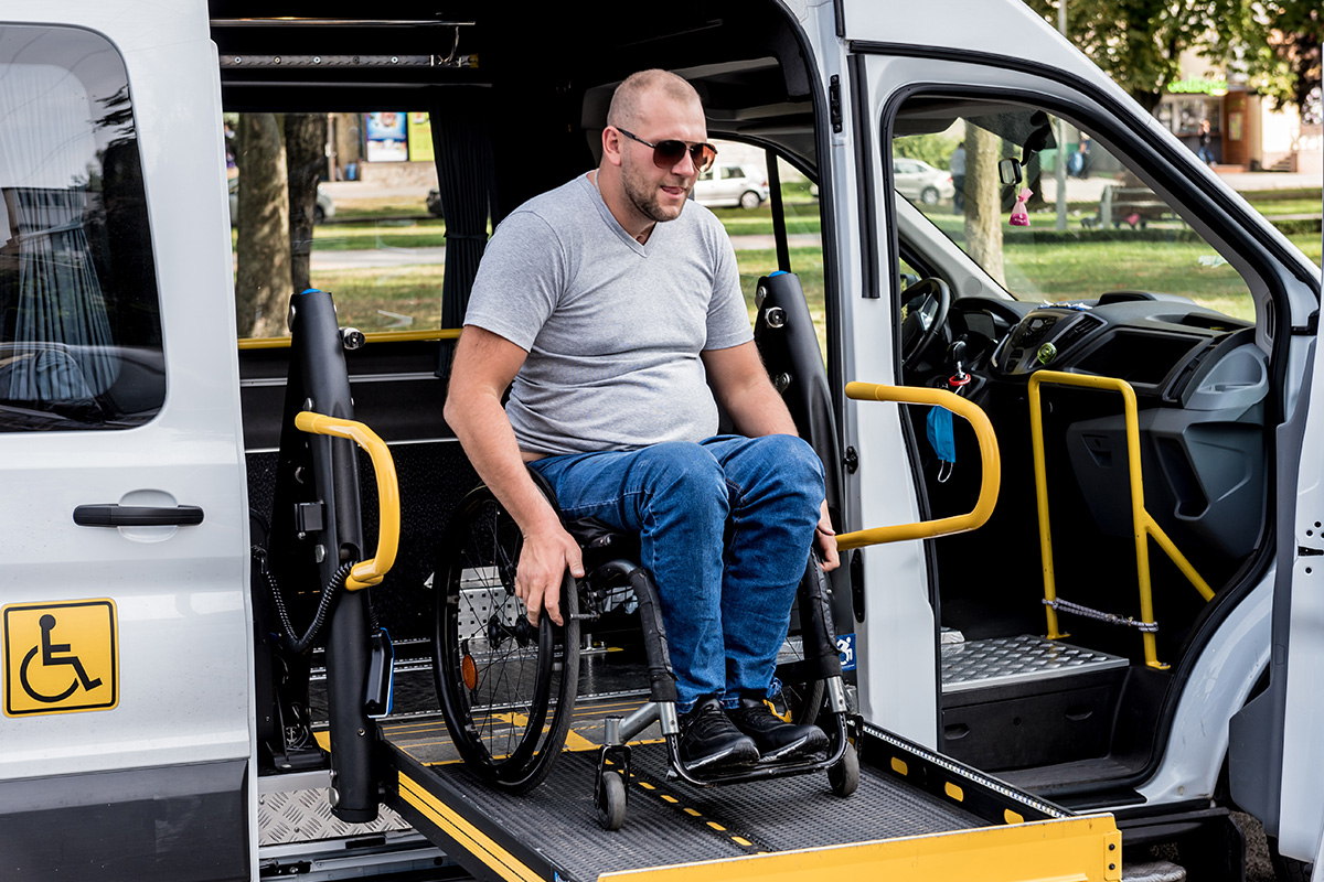 Ein Mann im Rollstuhl nutzt die Rampe eines Fahrzeuges